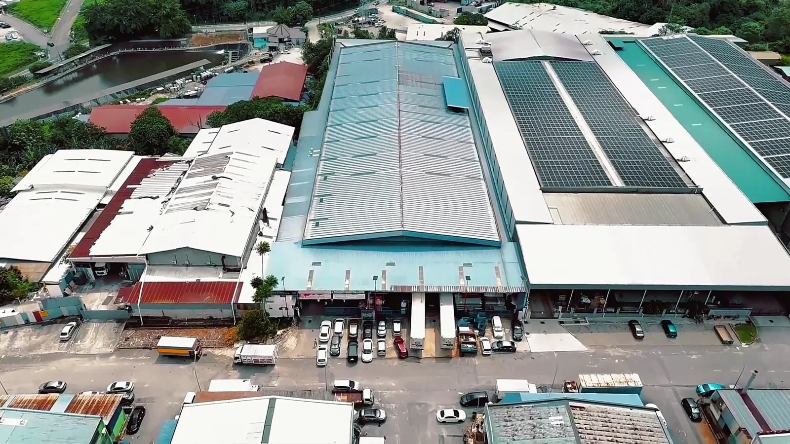 Aerial view of the Arctic cold-storage facility — warehouses with solar roofs and loading bays lined with refrigerated trailers